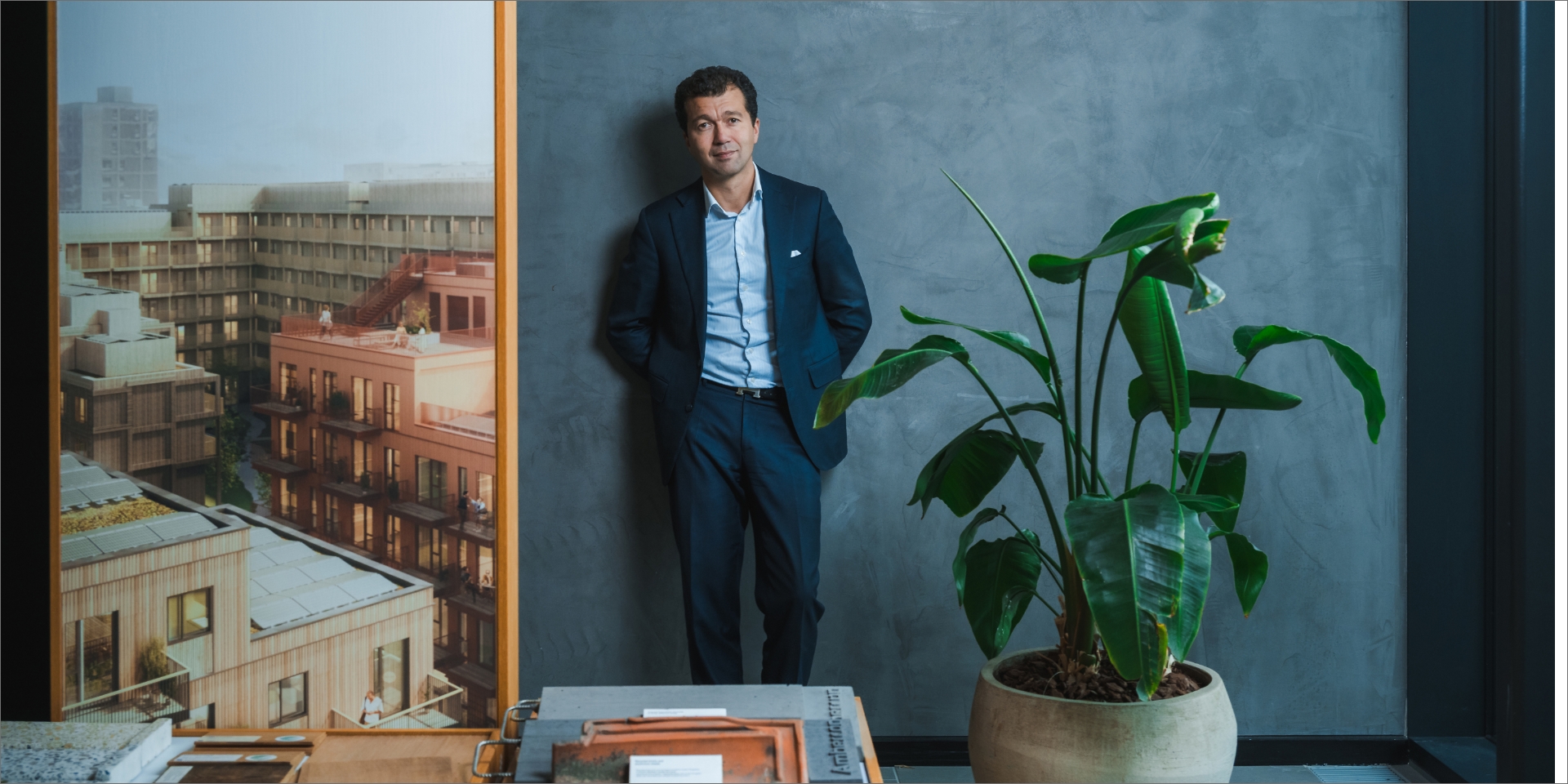 Dariush Rezai står ved siden af en grøn plante og et billede af nogle bygninger