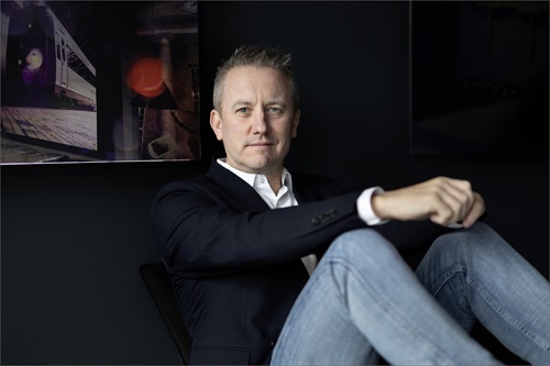 Jens Broch sidder lænet op ad en væg med foldet hænder