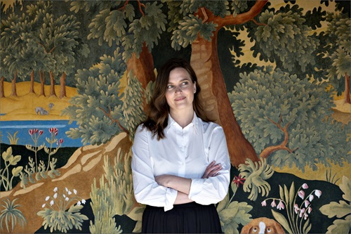 Julie Rokkjær Birch står foran et maleri med armene over kors