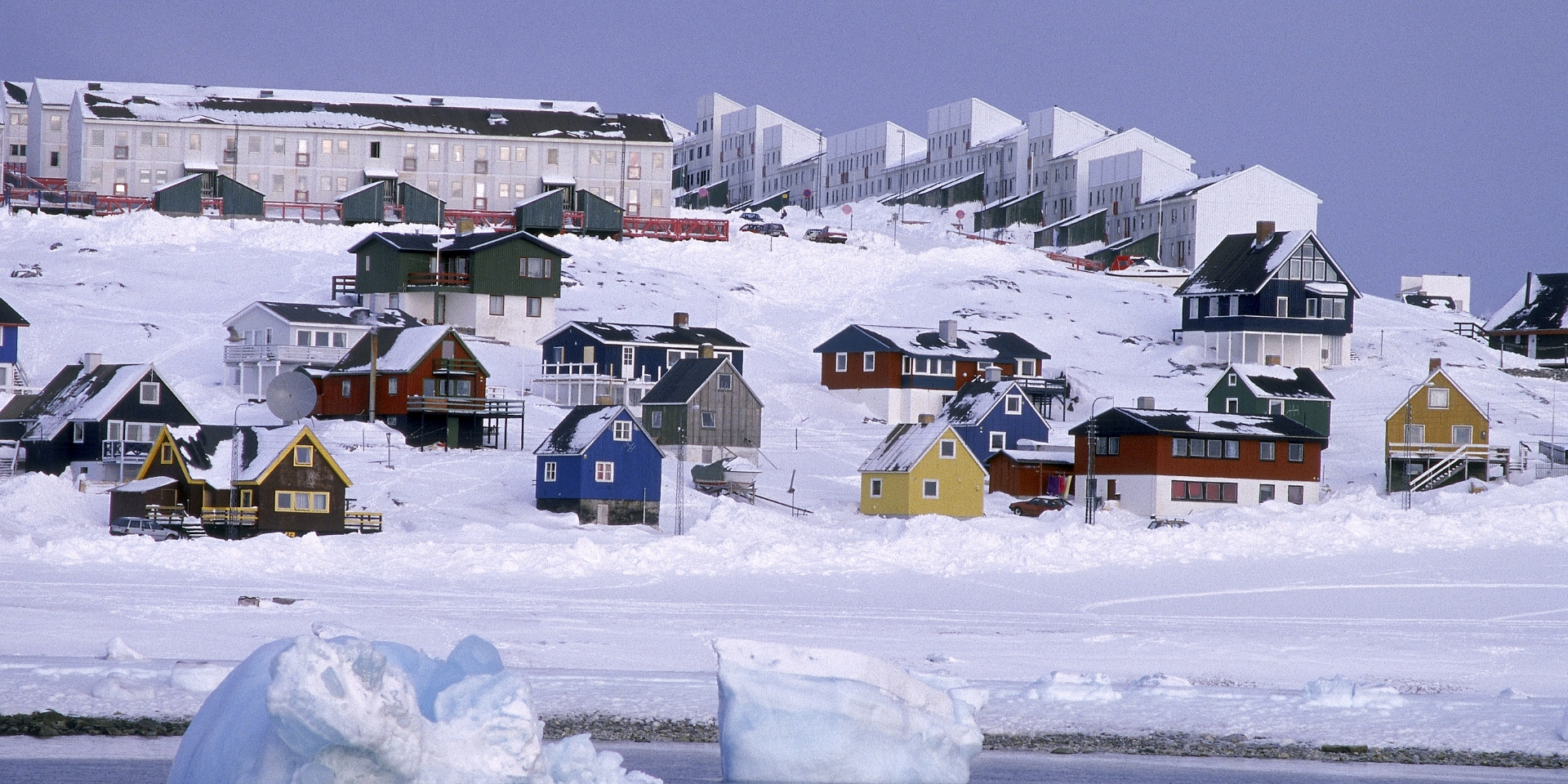 Et billede af Grønlands landskab med sne og huse