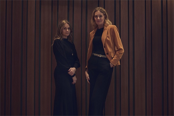Vibeke Lunding Gregersen og Louise Dinesen står ved siden af hinanden foran træpanel
