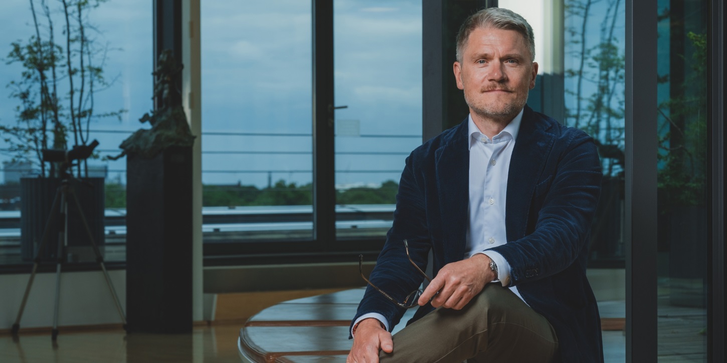 Martin Nyrop sidder på en bænk med krydsede ben
