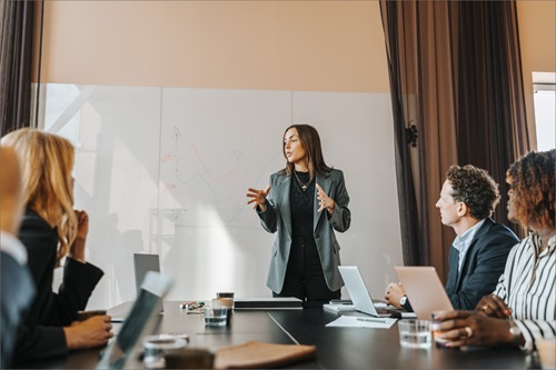 En kvinde står foran sine kolleger og præsenterer