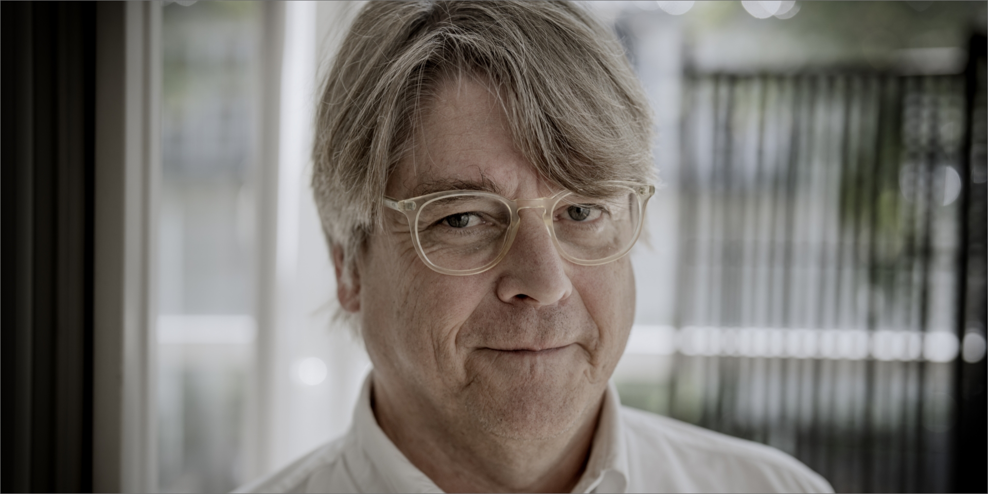 Peter Lund Madsen står i hvid skjorte og smiler