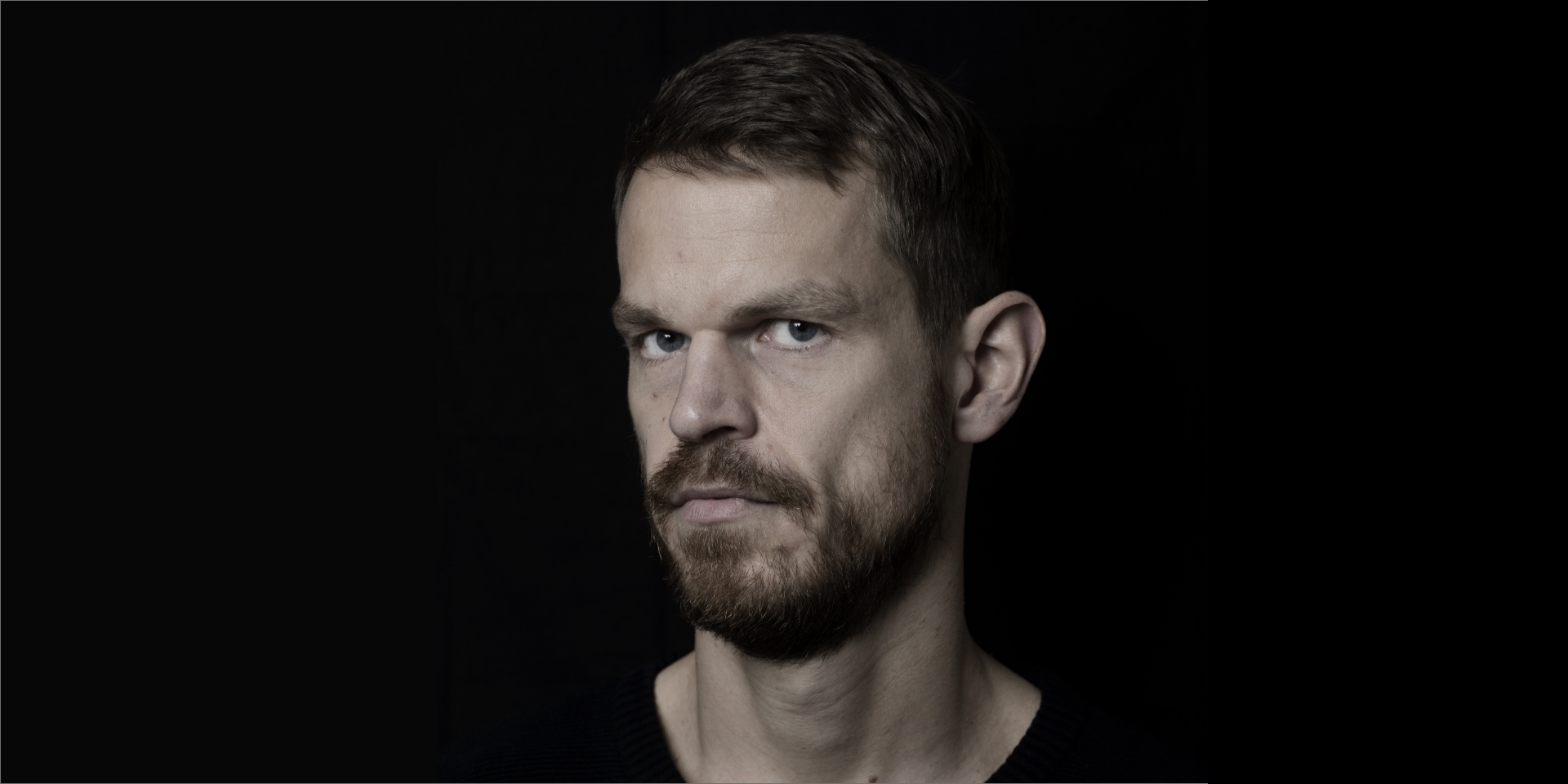 Svend Brinkmann står foran en sort baggrund i sort t-shirt