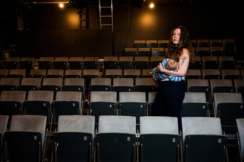 Anna Malzer holder sit barn i sine arme blandt sæderne i teatersalen