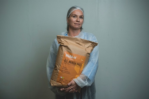 Aviaja Andersen står med en sæk maskmel iført hår net