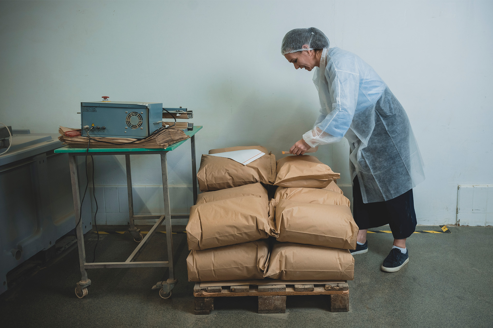 Aviaja Andersen står foran en palle med flere sække maskmel