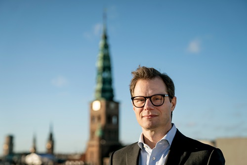 Carsten Egeriis står med flot bygning i baggrunden