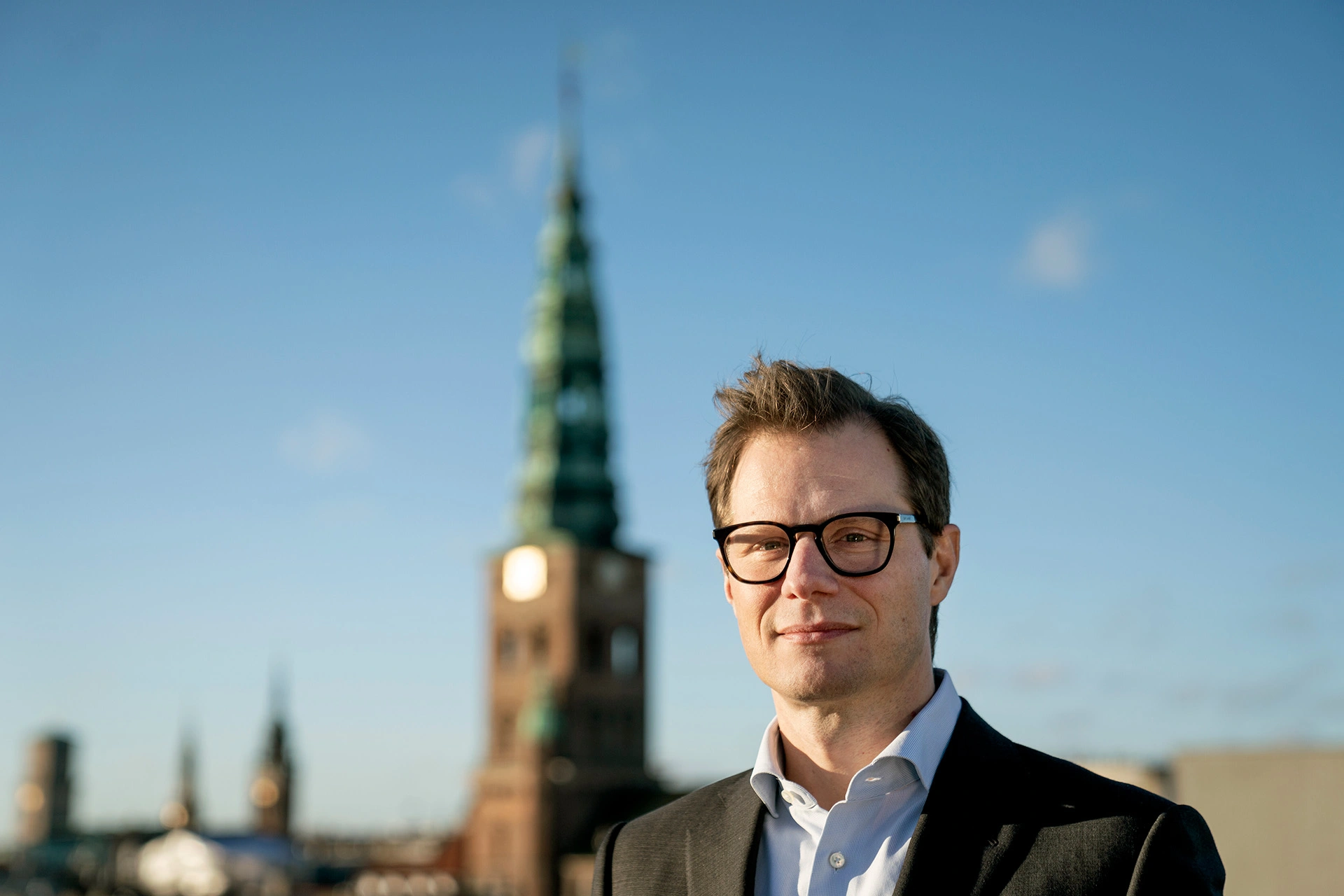 Carsten Egeriis står med flot bygning i baggrunden