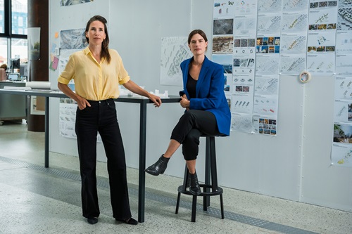 Nina Mathiesen og Mari Randsborg står og sidder ved et bord