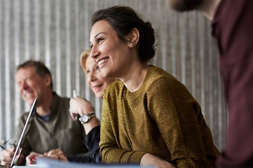 En masse mennesker sidder og smiler til et møde