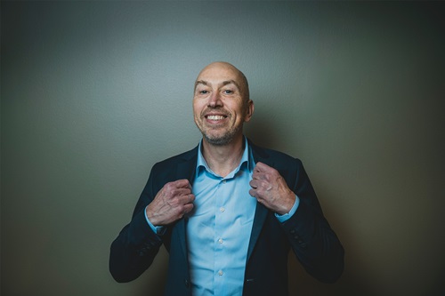 Jakob Keinicke Sørensen smiler til kameraret og holder i kraven på hans skjorte