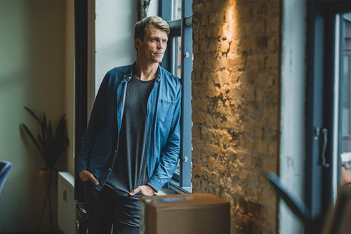 Nomineret til Årets Leder 2022, Jeppe Rindom kigger ud af et vindue mens han læner sig op af væggen