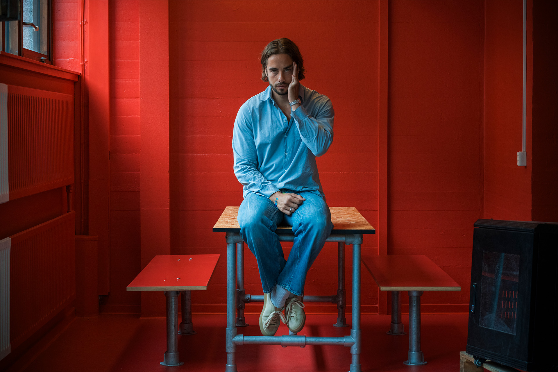 Jesper Thiel Thomsen sidder på et bord i et rødt lokale