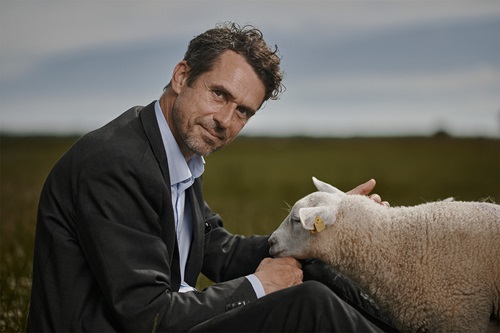 Jonas Engberg sidder på en mark med et lam