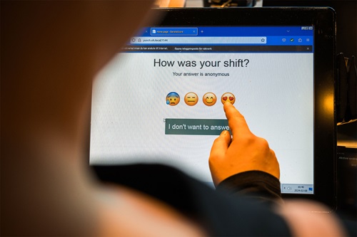 En medarbejder benytter trivselsmålingsskærmen med smileyer