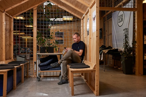 Lars Riis sidder på en bænk på ELSK's kontor med sin telefon