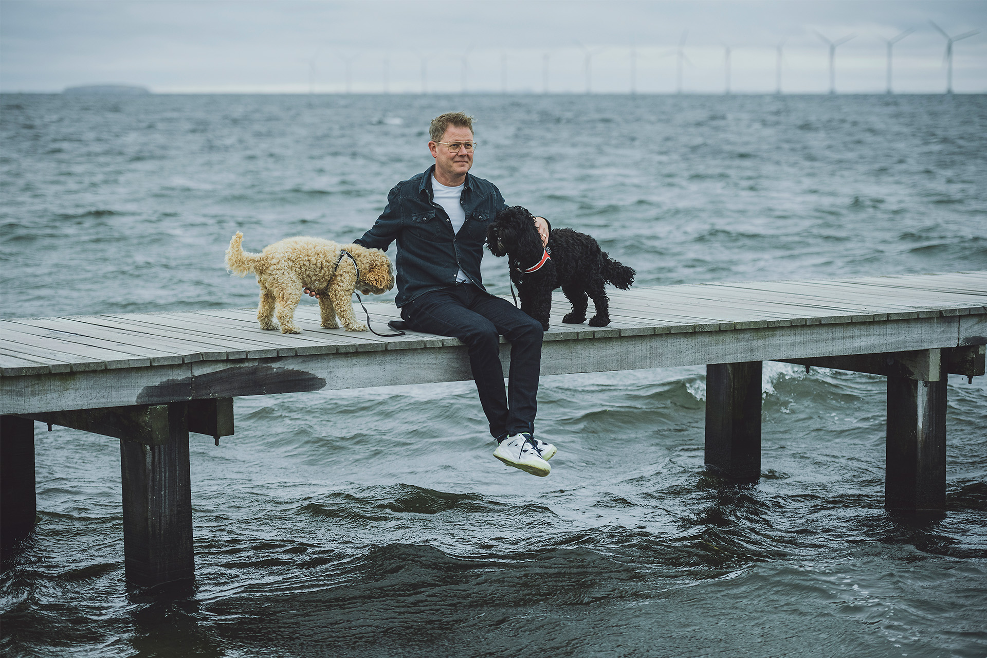 Lars Sander Matjeka sidder på en badebro med sine hunde på Amager Strandpark