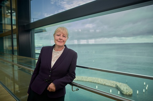 Marianne Kock står ved et rækværk foran en smuk udsigt