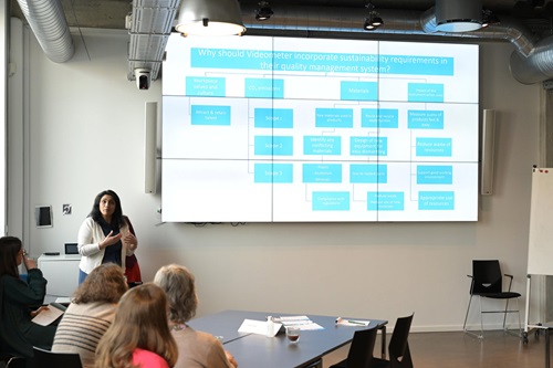 Shahida Hamid taler til et kursus med en storskærm bag sig