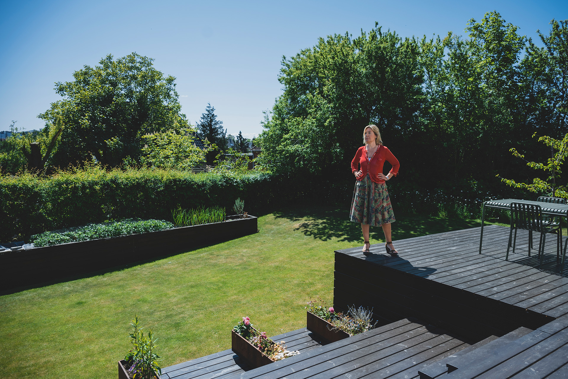 Mette Davidsen Nielsen står på sin terrasse i solskin