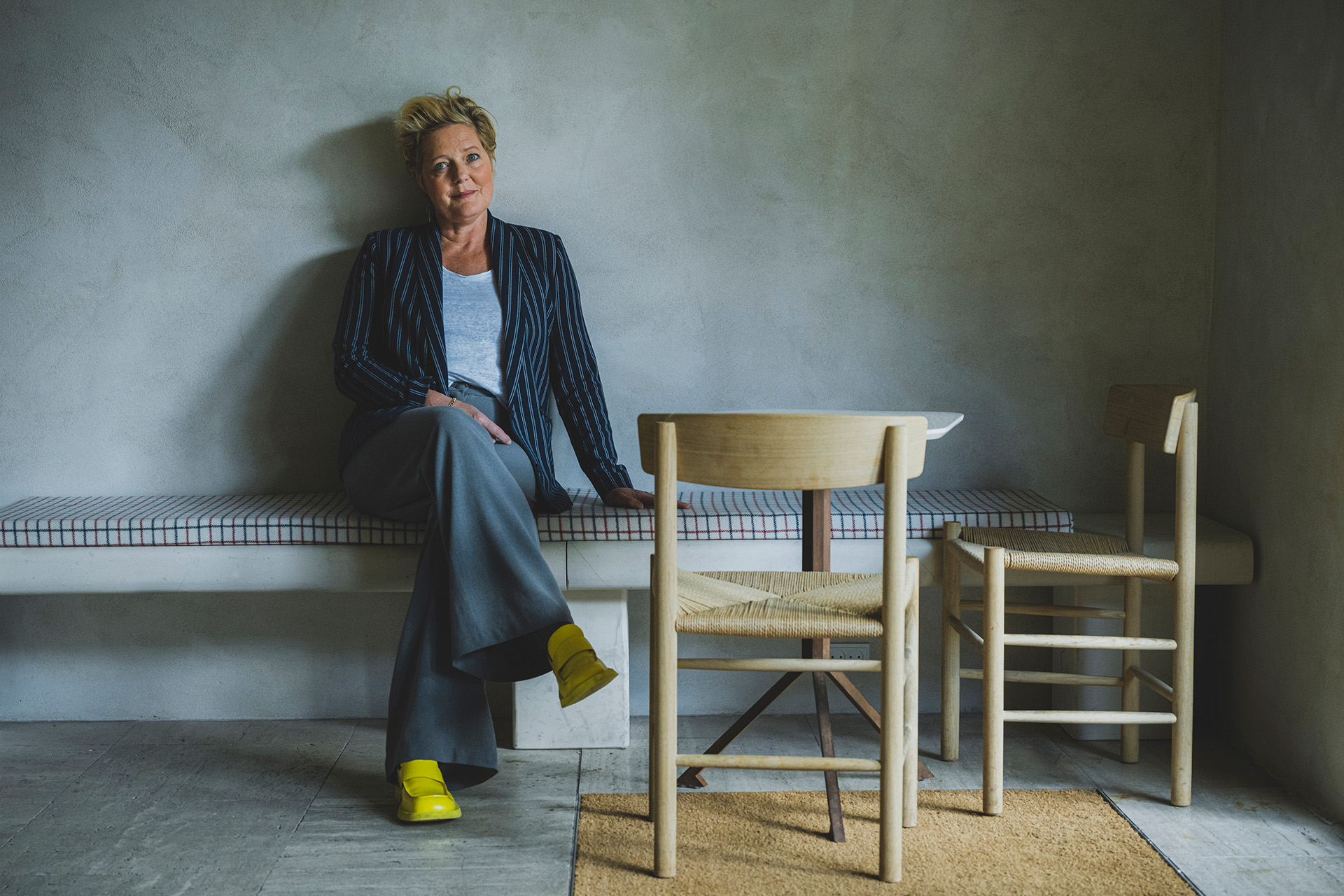 Mette Wolf sidder på en bænk ved siden af to stole
