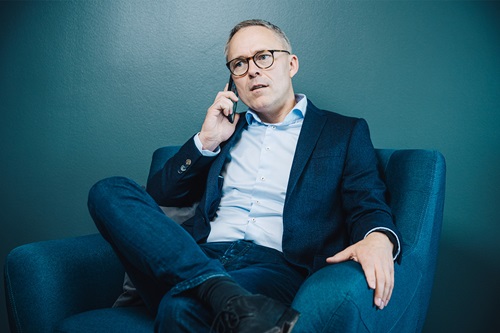 Michael Løve sidder i en lænestol og taler i telefon