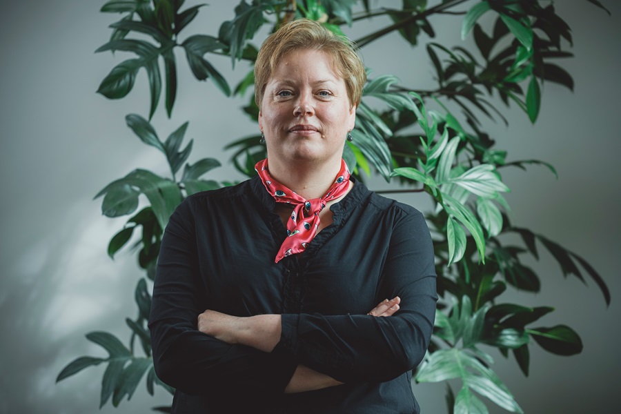Nina Jørgensen står foran en plante med krydsede arme