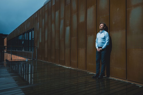 Ole Krogh Petersen står og læner sig op ad en væg udenfor