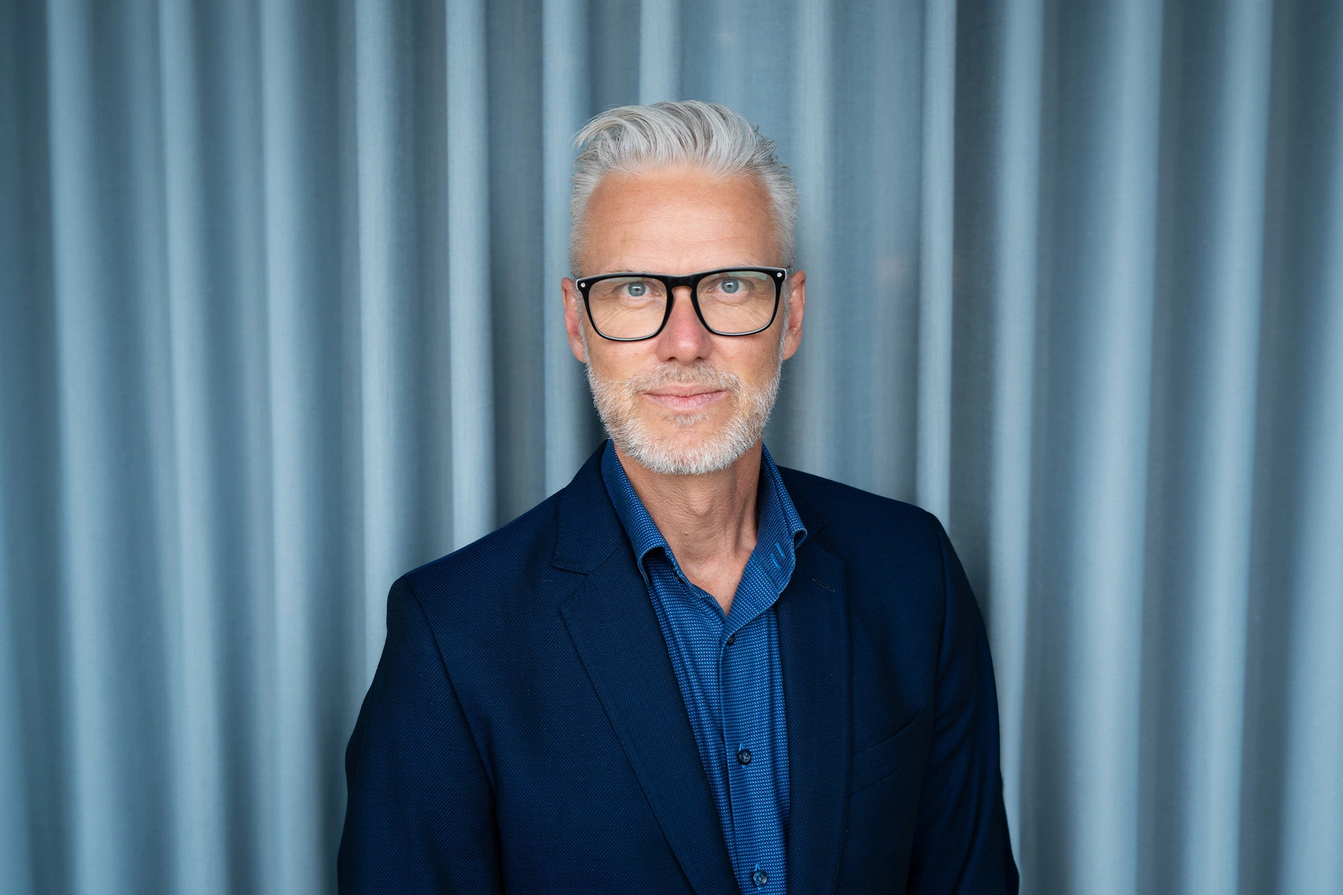 Palle Knudsen står foran en blå baggrund