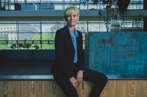 Pernille Sindby sidder på en kant og smiler til kameraret