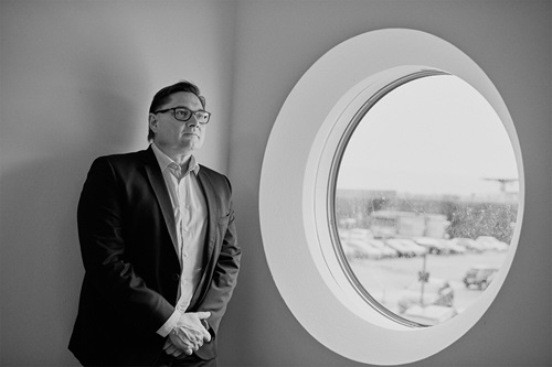 Sort hvid billede af Peter Kjær ved siden af et vindue