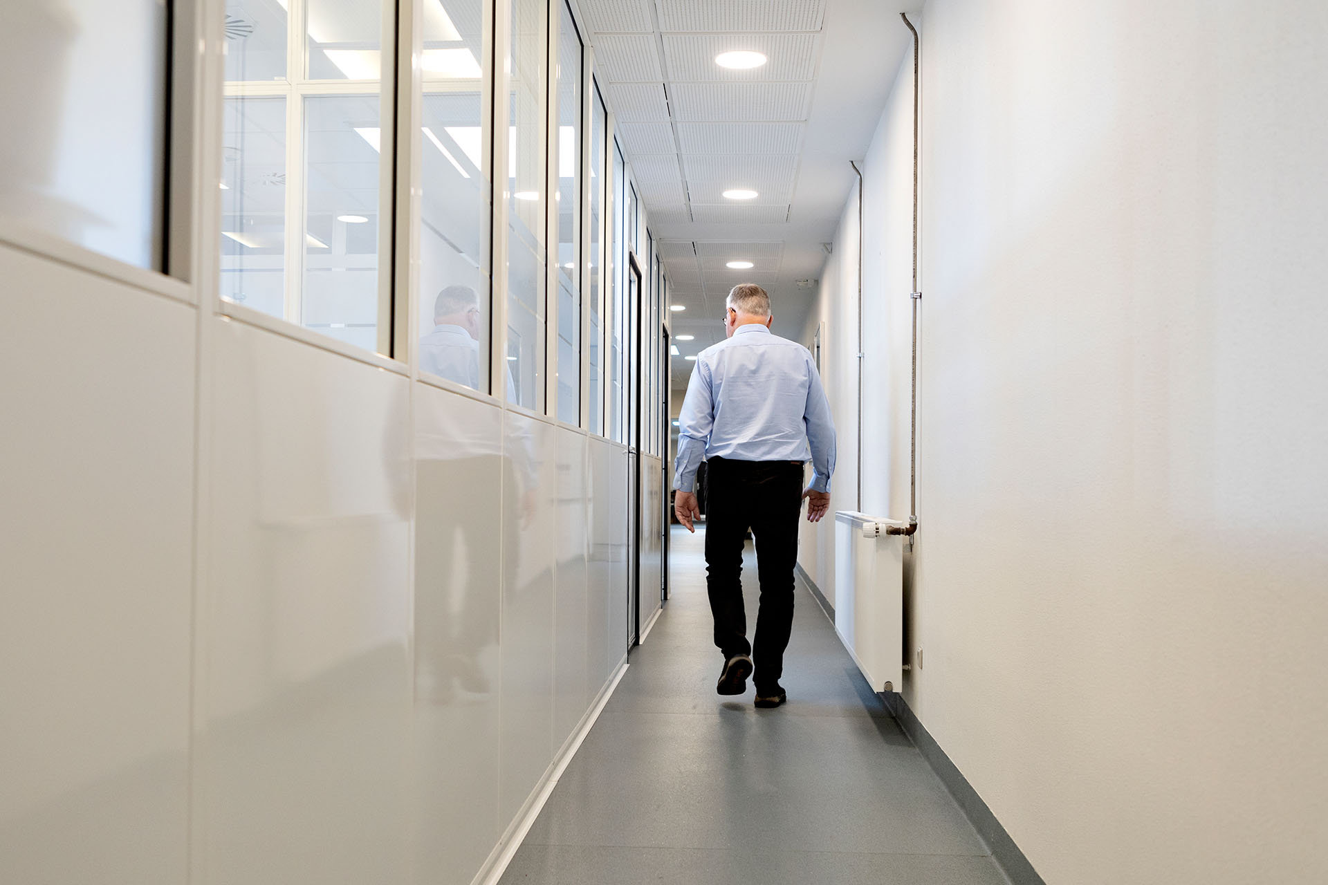 Poul Pedersen går ned ad en lang hvid gang