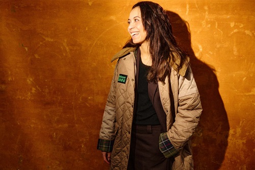 Rebecca Holmberg Jensen griner og står foran en orange væg