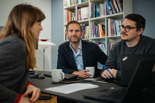 Tommy Zwicky sidder mellem to kollegaer og snakker
