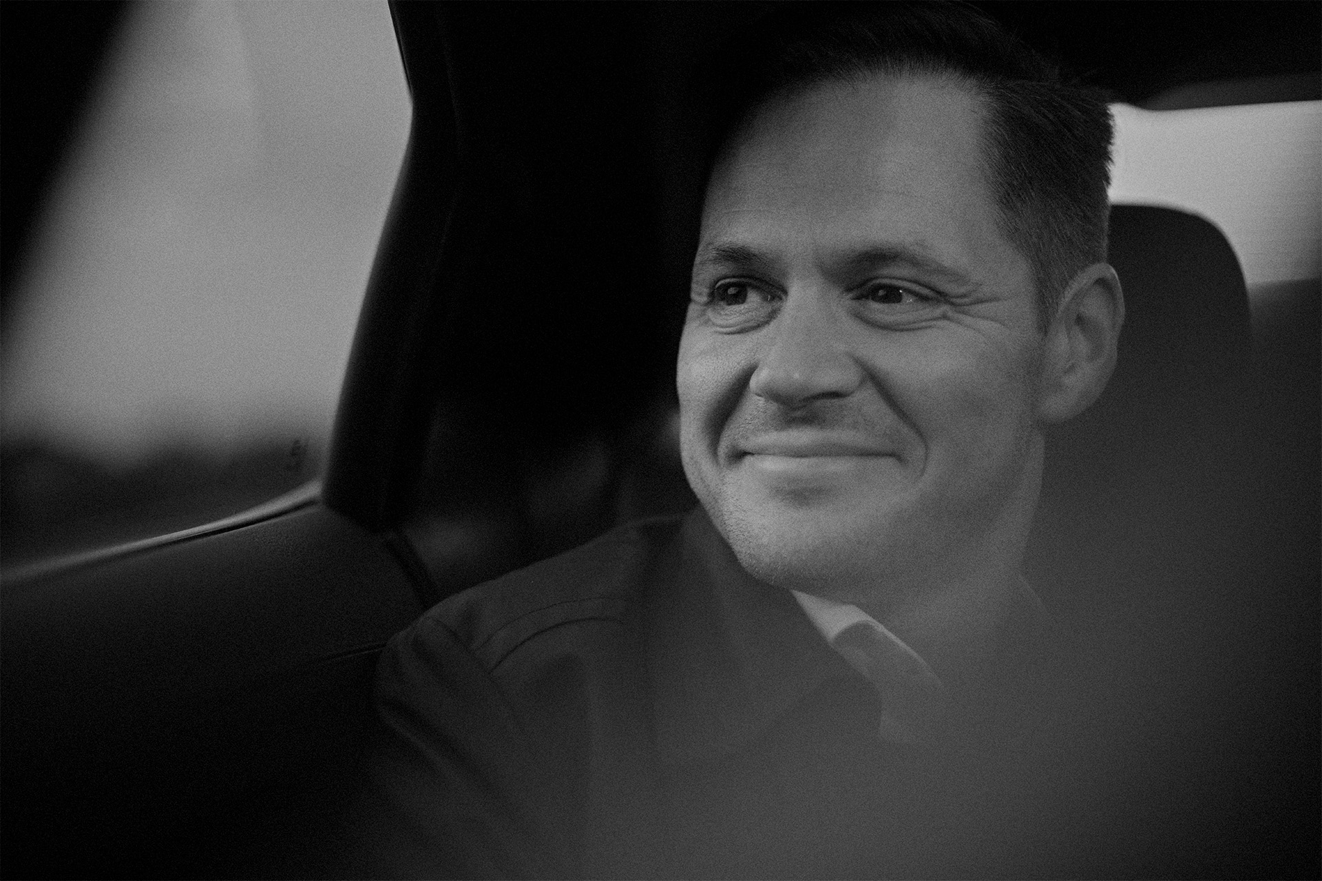 Ulrik Drejsig sidder i sin bil og smiler i sort hvid