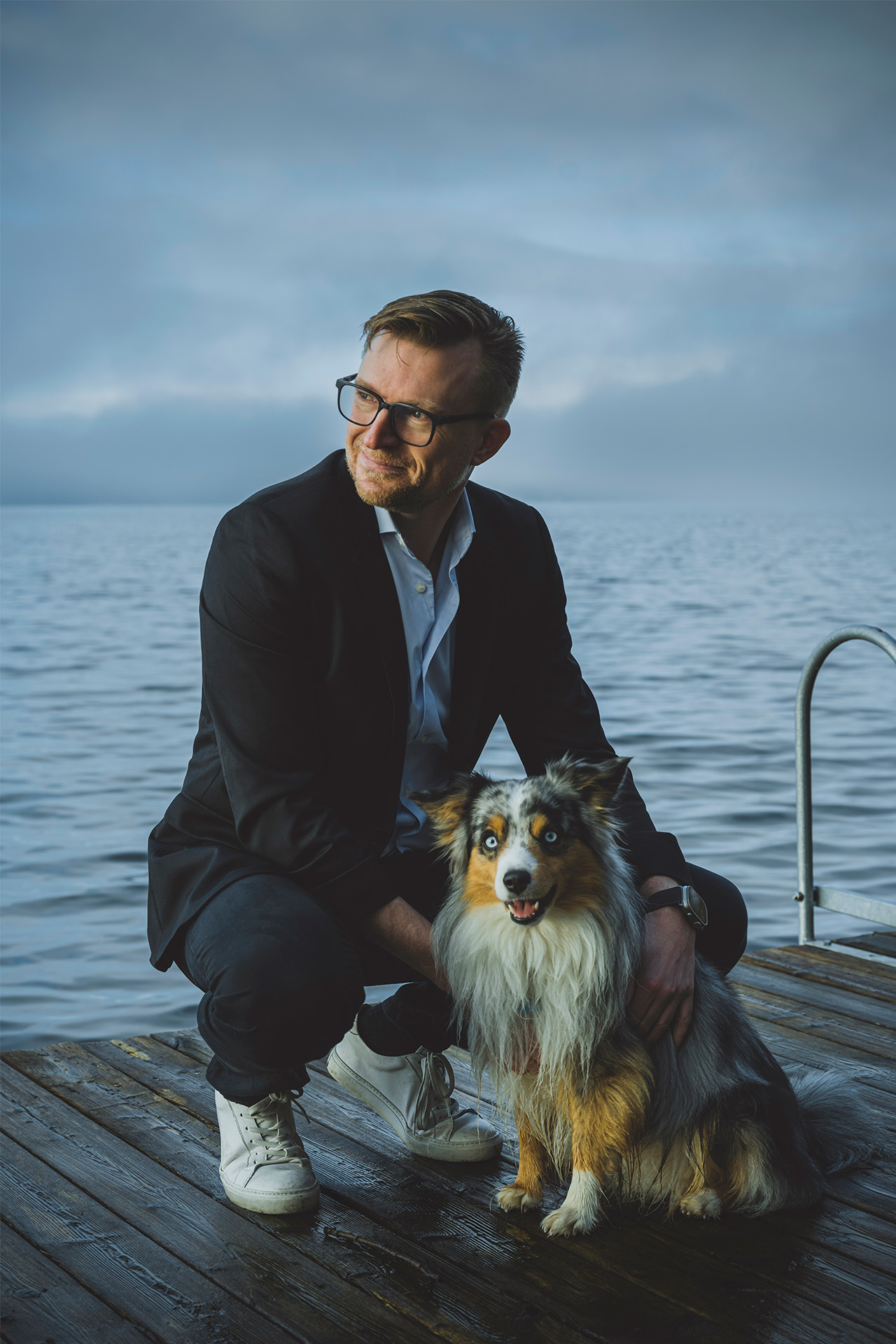 Eske Gunge knæler på en badebro og kæler med sin hund