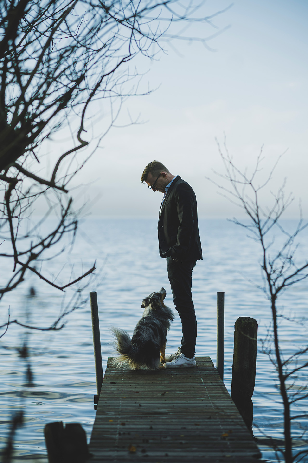 Eske Gunge står på en badebro og ser ned på sin hund