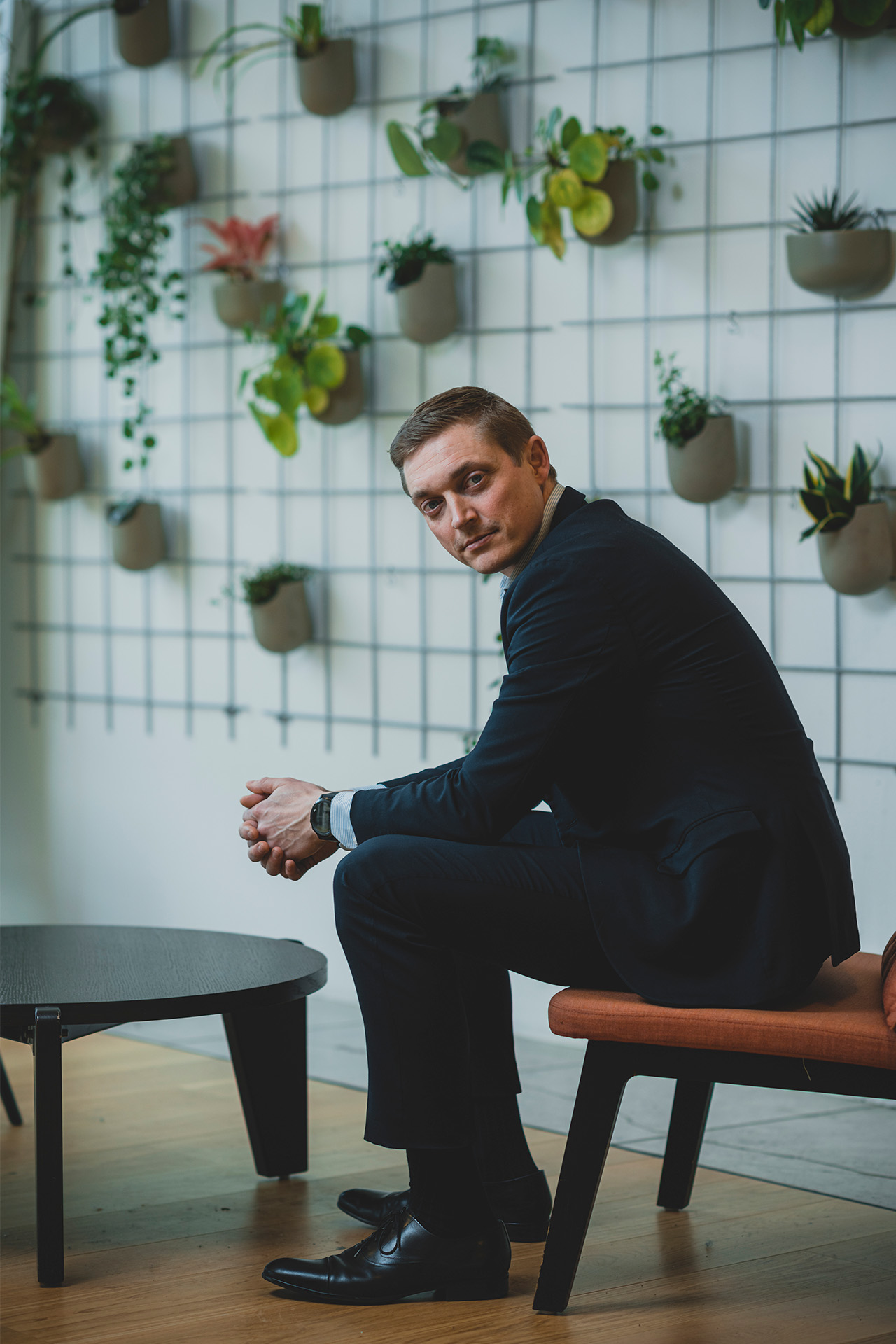 Frederik Nexøe-Larsen sidder på en stol foran en væg med planter