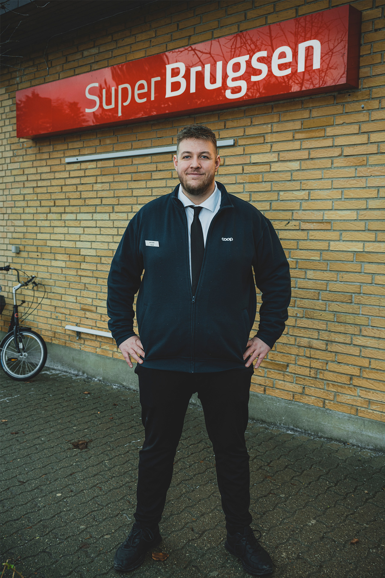 Portrætbillede af Jonas Schmidt ude foran en SuperBrugsen butik