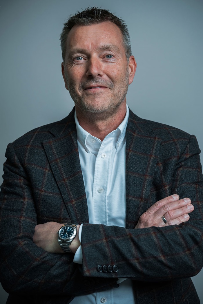 Kim Haldne står foran en grå baggrund med hånden i lommen