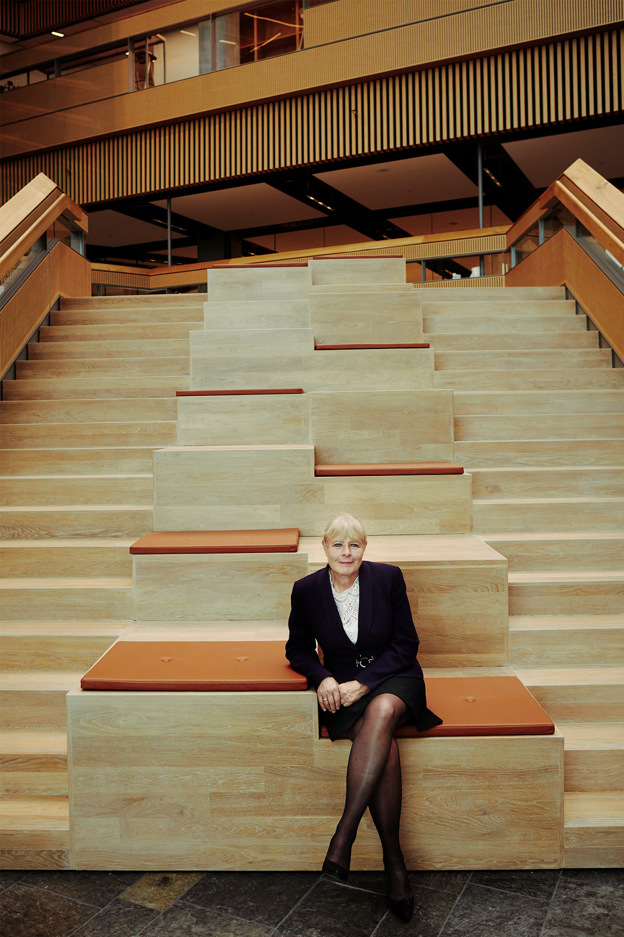 Marianne Kock sidder på en trappe på kontoret