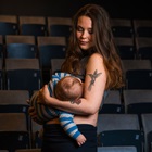 Anna Malzer holder sit barn i sine arme blandt sæderne i teatersalen