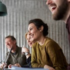 En masse mennesker sidder og smiler til et møde