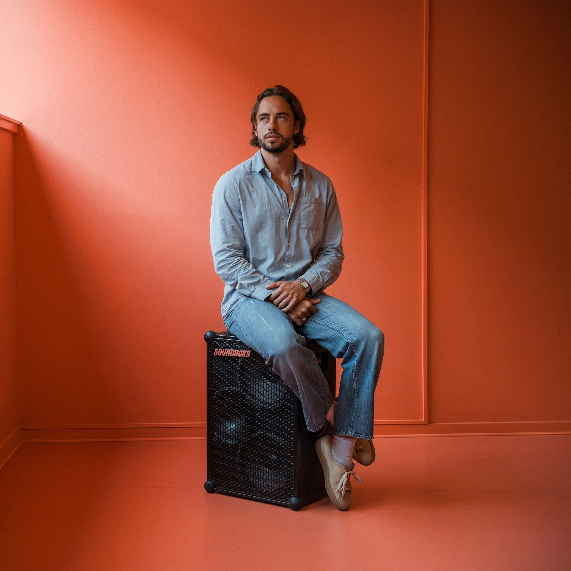 Jesper Thiel Thomsen sidder på en soundboks i et rødt lokale