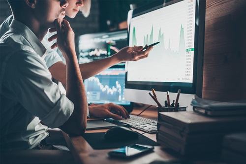 Mand og kvinde foran computerskærm med statistik på