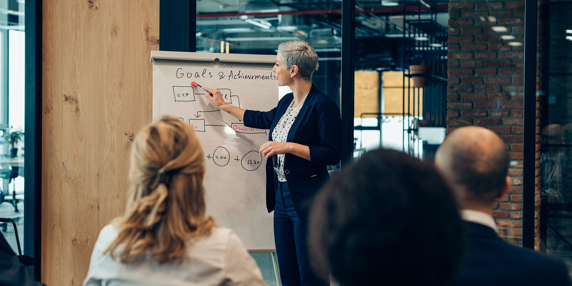 Kvinde står ved tavle og fortæller om ny strategi