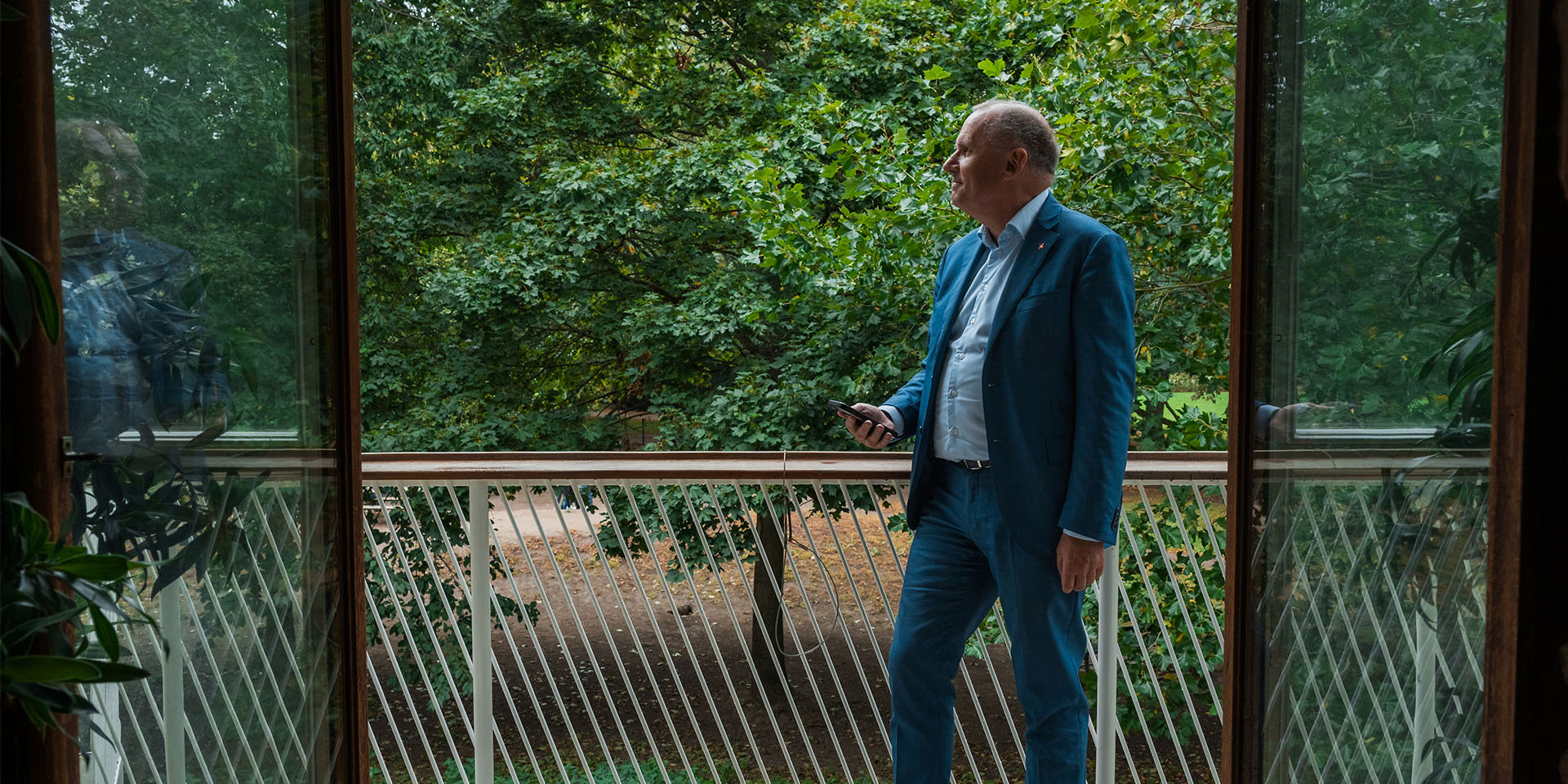 Anders Ladekarl står på en terrasse med grønt buskads i baggrunden