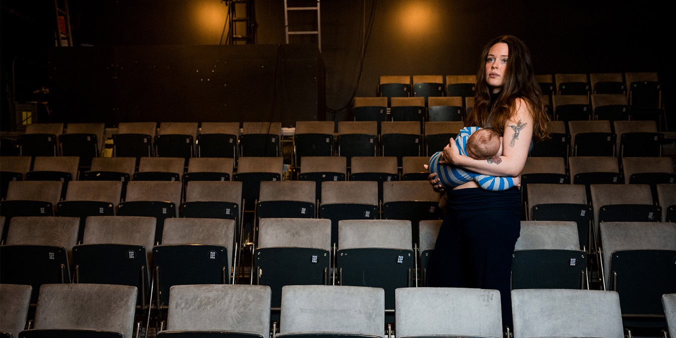 Anna Malzer holder sit barn i sine arme blandt sæderne i teatersalen